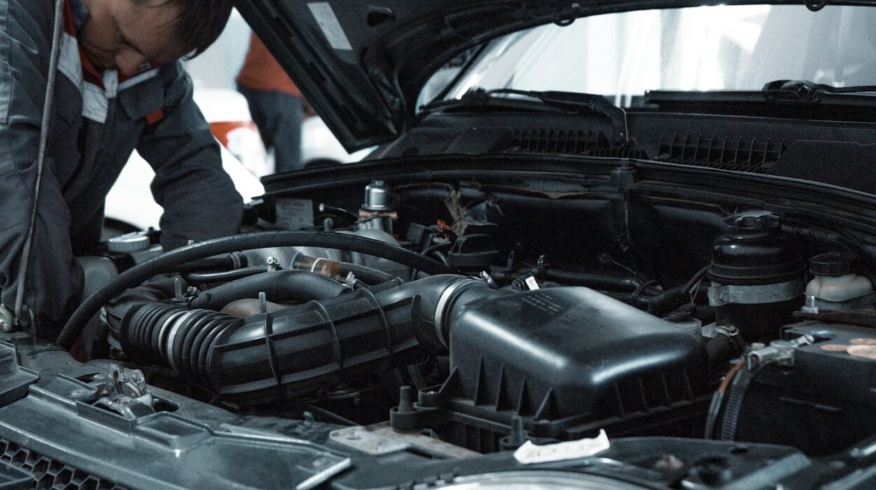 Mechanic in a grey uniform inspecting a car engine in a workshop