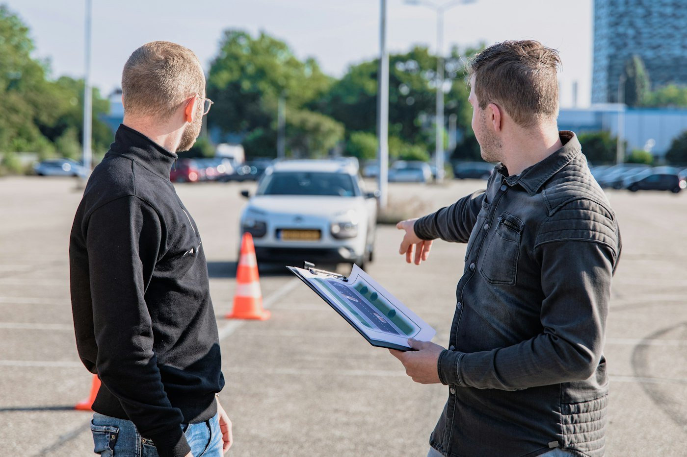 Driving examiner with a clipboard beside a car