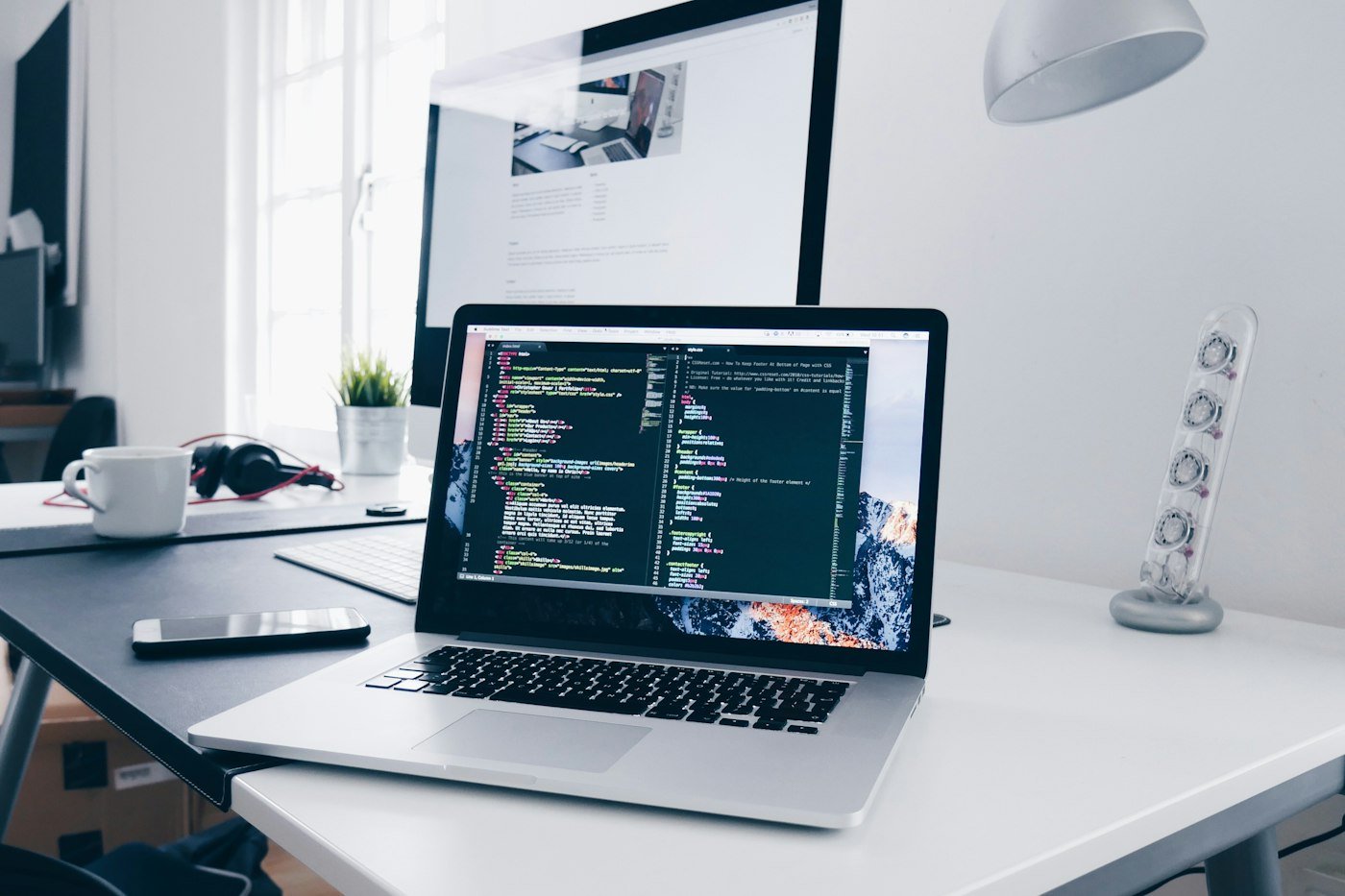 Laptop showing website code on a desk