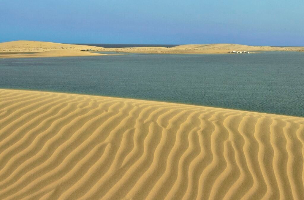 Calm water of the Inland Sea beside rippled dunes