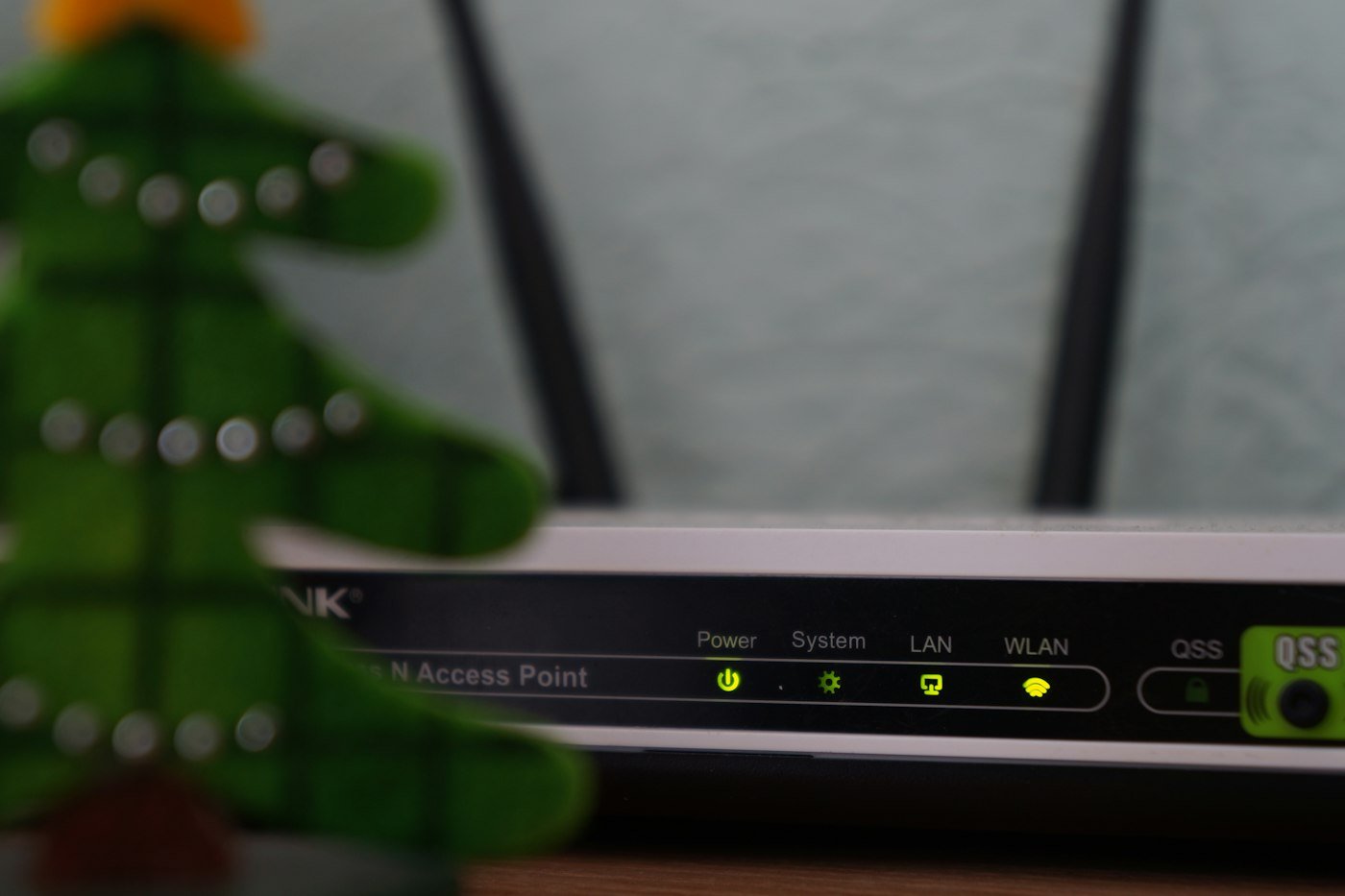 A wireless router with two antennas and lit status lights on a table